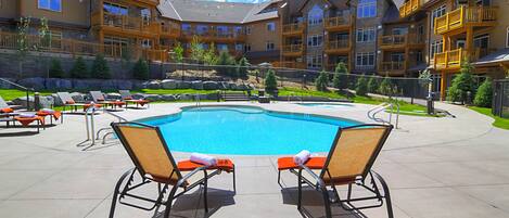 A pool area with lounge chairs and a clear blue pool.