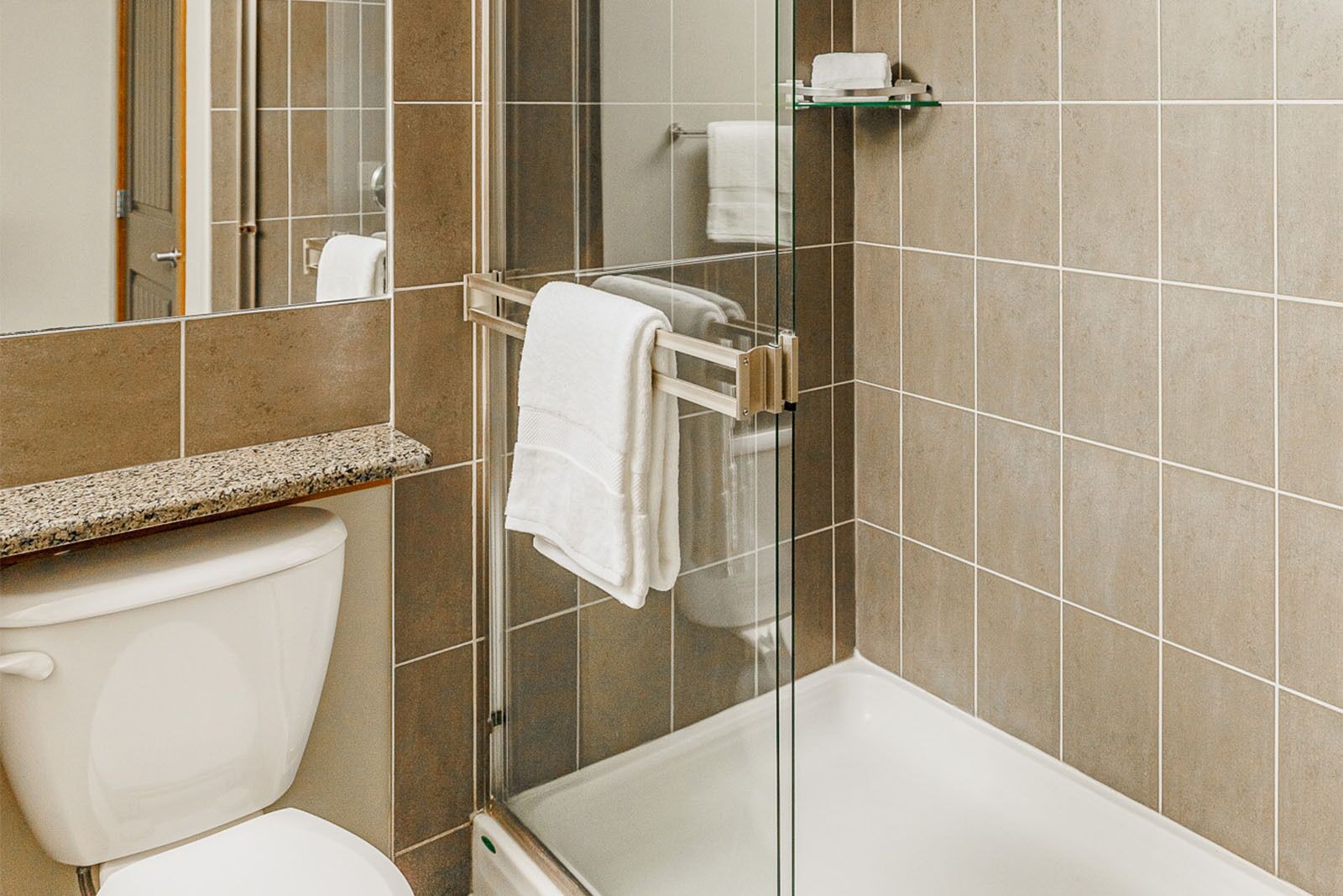 A bathroom with a toilet, a glass shower enclosure, and a bathtub.