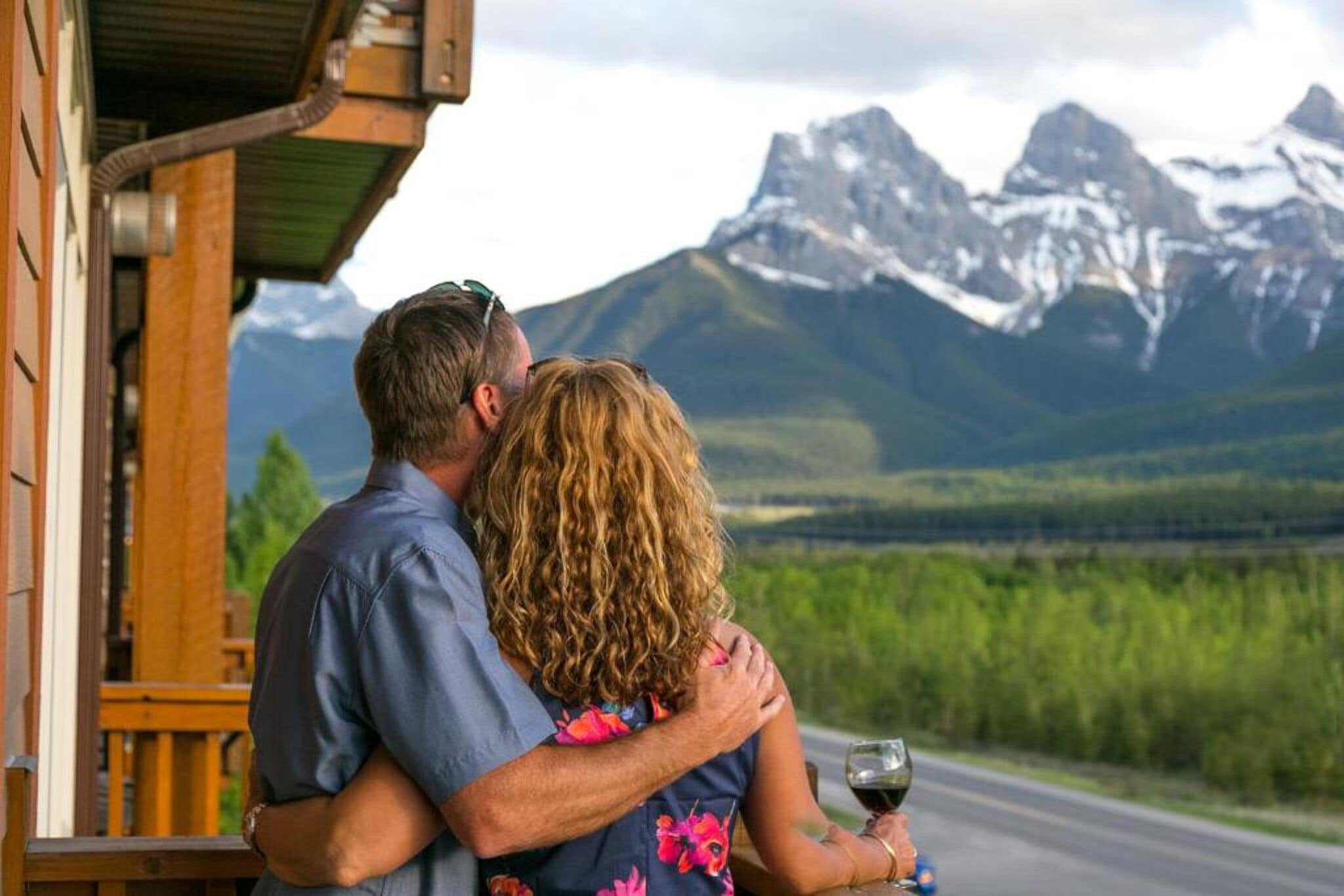 Una pareja abrazándose en un porche con vistas a la montaña.