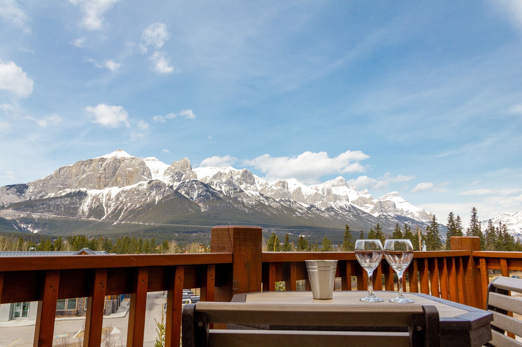 A table with two wine glasses and a bucket, overlooking a mountain range.