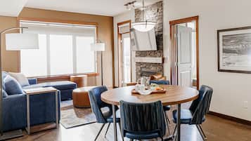 A modern dining area with a round wooden table, blue upholstered chairs, and a stone accent wall.