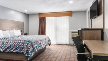 A hotel room with a bed, a desk, a chair, a TV, and a window with curtains.