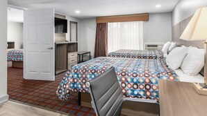 Habitación de hotel con dos camas, un escritorio, una silla, un armario y una ventana con cortinas.