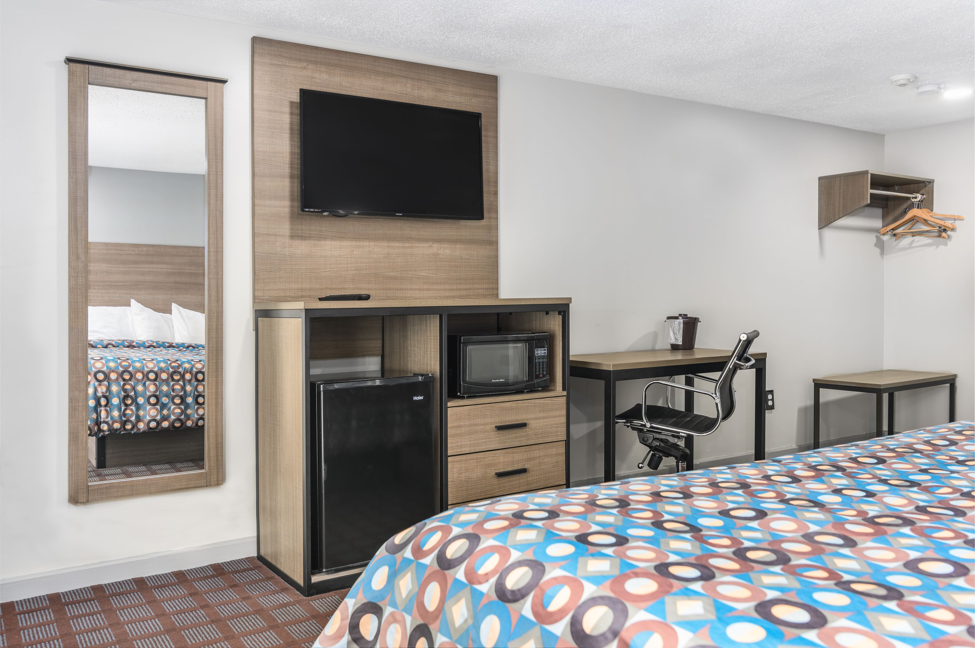 A hotel room with a bed, a desk with a computer, a microwave, and a TV.