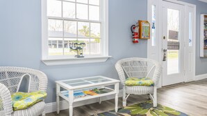 Una habitación con dos sillones de mimbre, una mesita blanca y una ventana con vistas.
