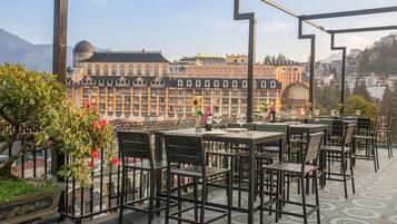 Una terraza al aire libre con mesas y sillas, una planta en maceta y vistas de un edificio histórico con múltiples ventanas y una cúpula.