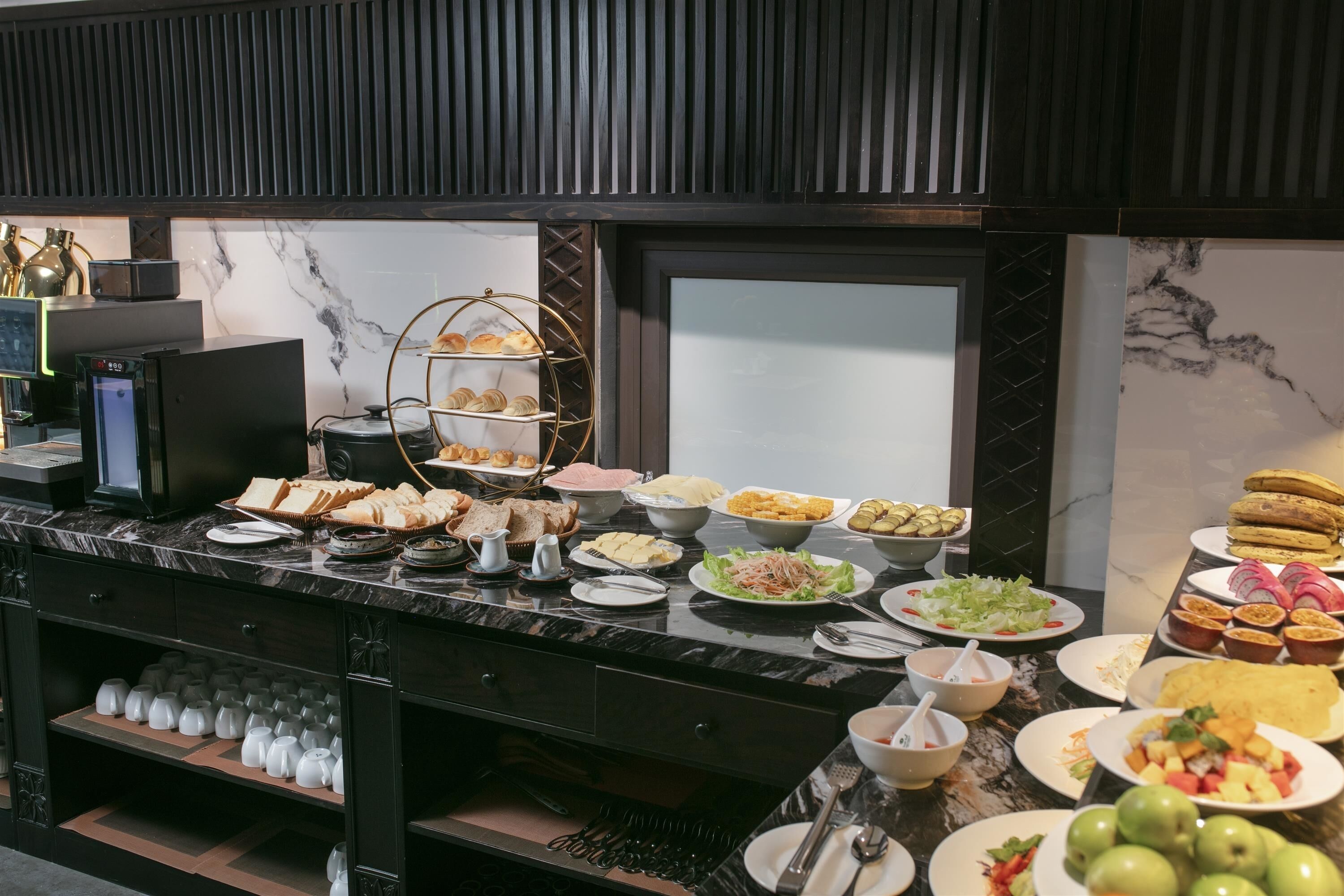 Buffet com diversos alimentos, máquina de café e refrigerador de vinhos.