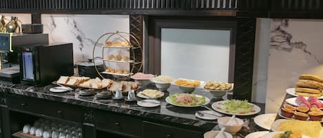Buffet com diversos alimentos, máquina de café e refrigerador de vinhos.