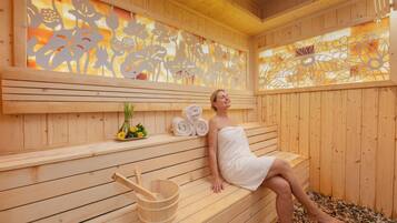 A wooden sauna with benches, a wooden bucket, and towels.