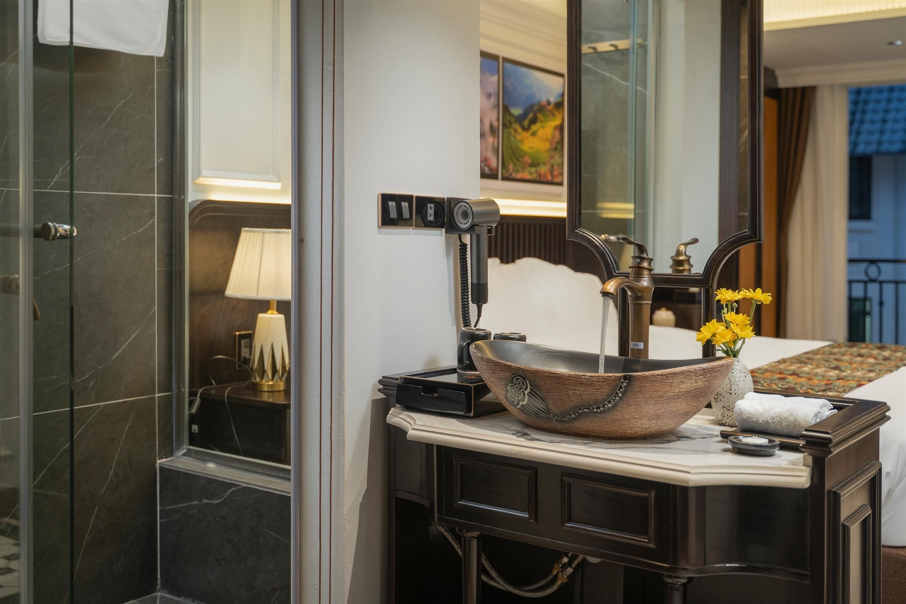 A bathroom with a large mirror, a vessel sink, a towel, and a lamp.