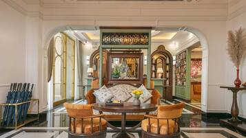 A formal dining area with a round table, two chairs, and a decorative mirror.