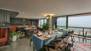 Un restaurante con mesas dispuestas para comer, un balcón con vistas y una pared decorada.