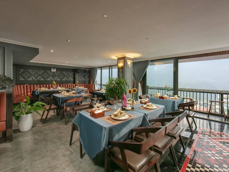 Un restaurante con mesas dispuestas para comer, un balcón con vistas y una pared decorada.