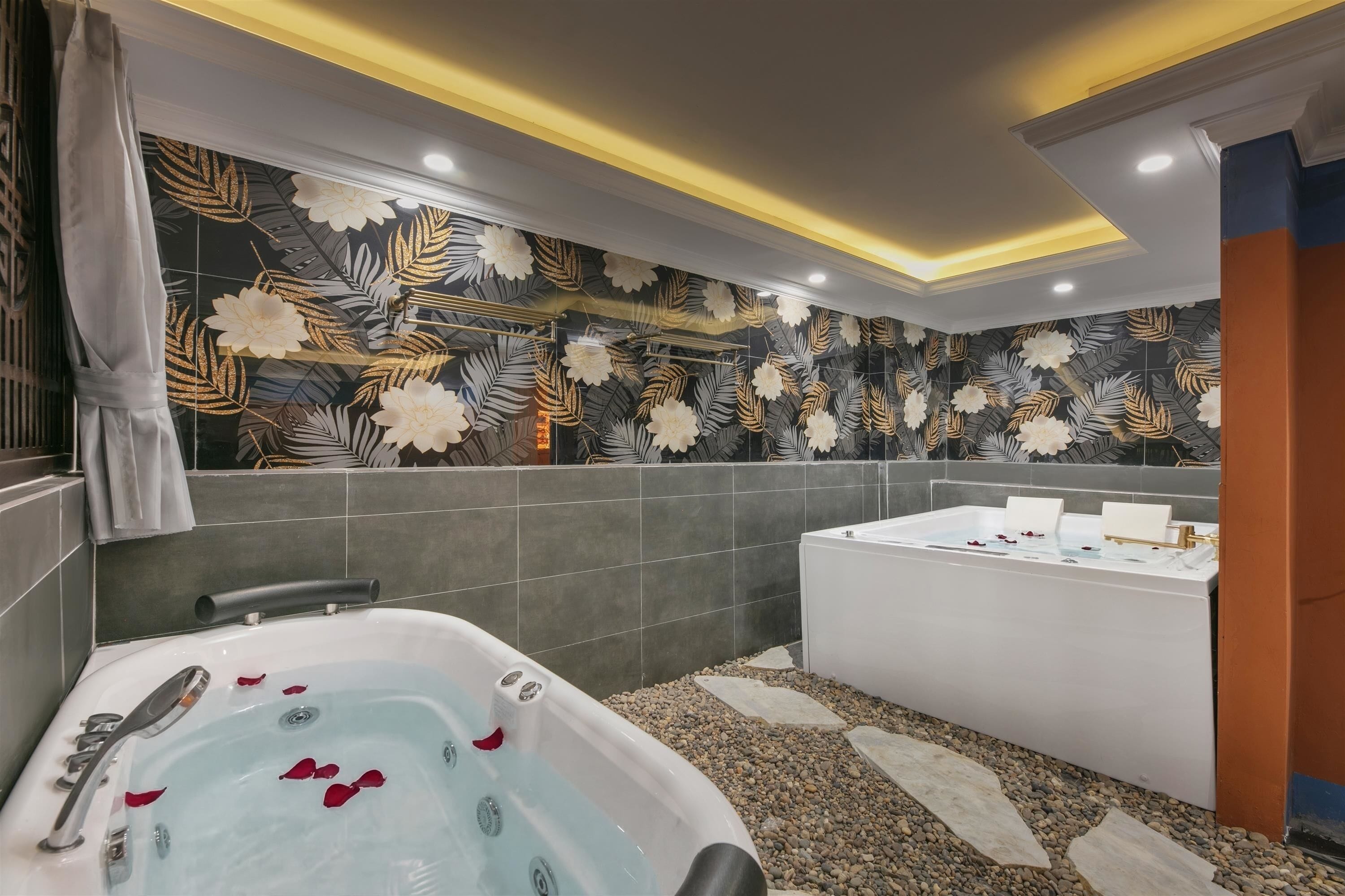 A modern bathroom with a large bathtub, a separate shower area, and a decorative wall with a leaf pattern.