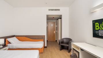 Habitación de hotel con dos camas, un escritorio, una silla, un armario y un letrero en la pared.