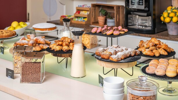 A buffet with various pastries and desserts, including croissants and donuts, and a coffee machine in the background. - B&B Hotel Eurorest Conegliano (Conegliano)