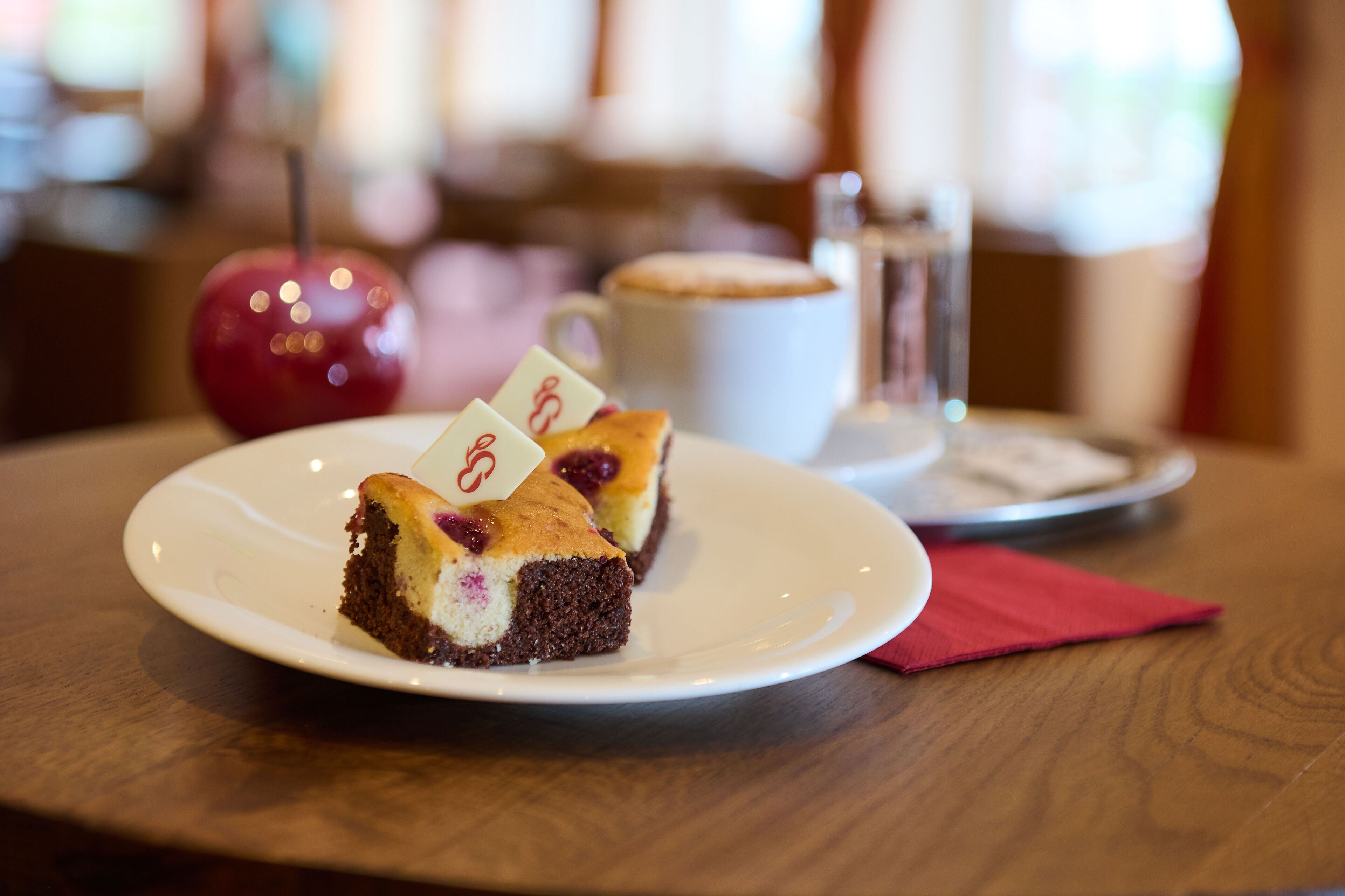 A slice of cake on a plate with a red napkin beside it.
