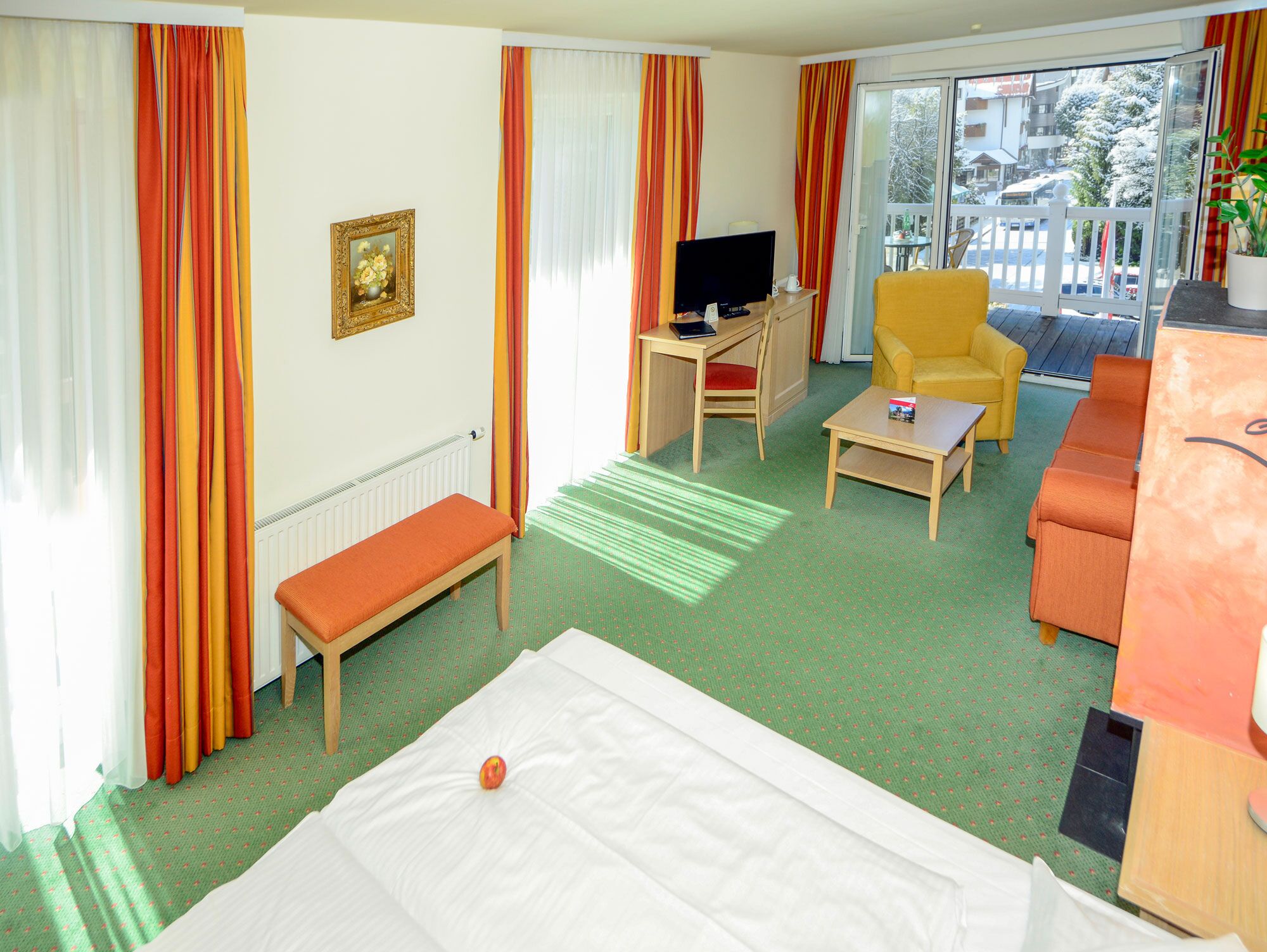 A hotel room with a bed, a desk, a chair, a sofa, and a television.