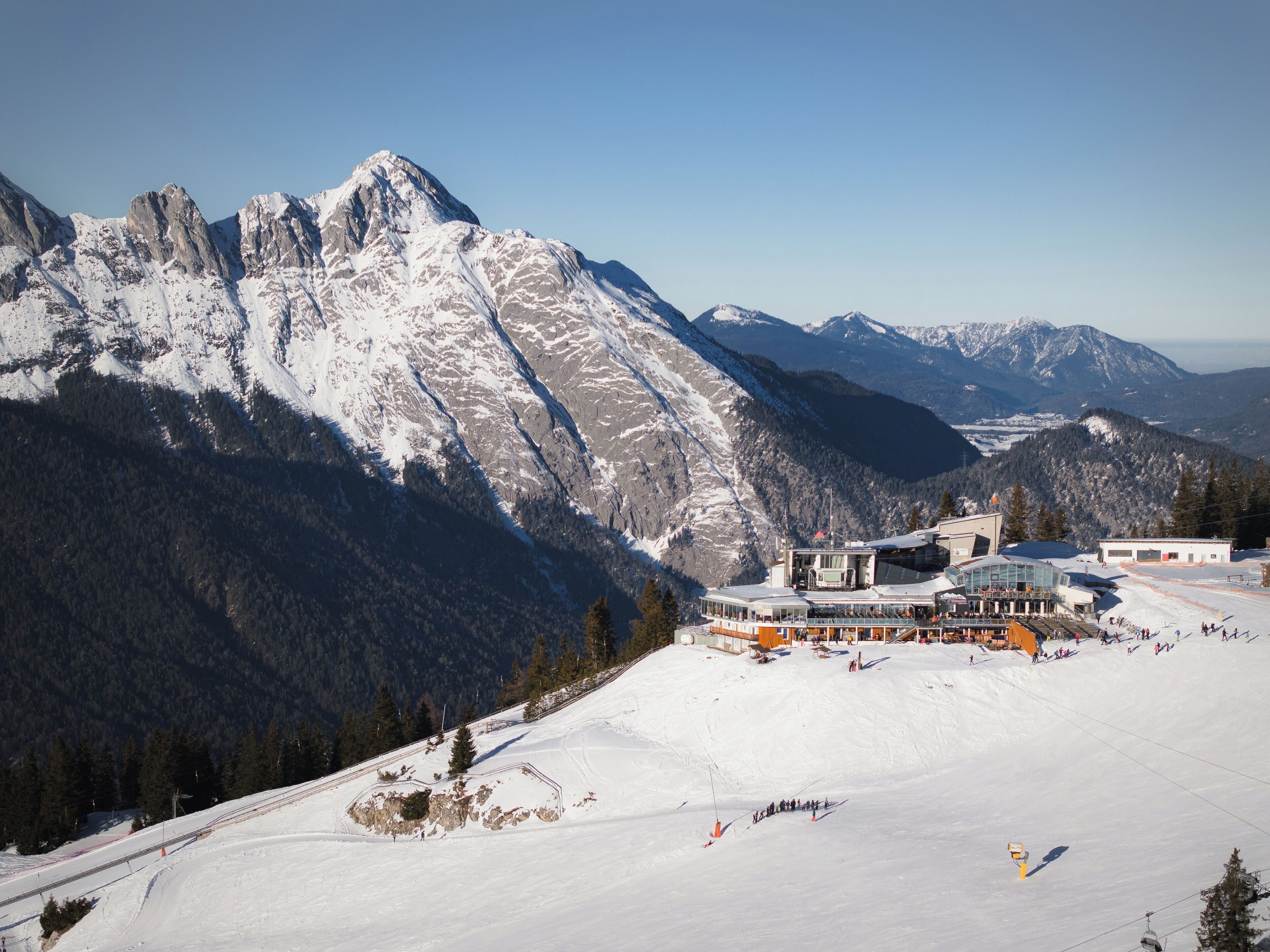Un complejo turístico de montaña con laderas nevadas, un telesilla y un edificio con fachada de vidrio.