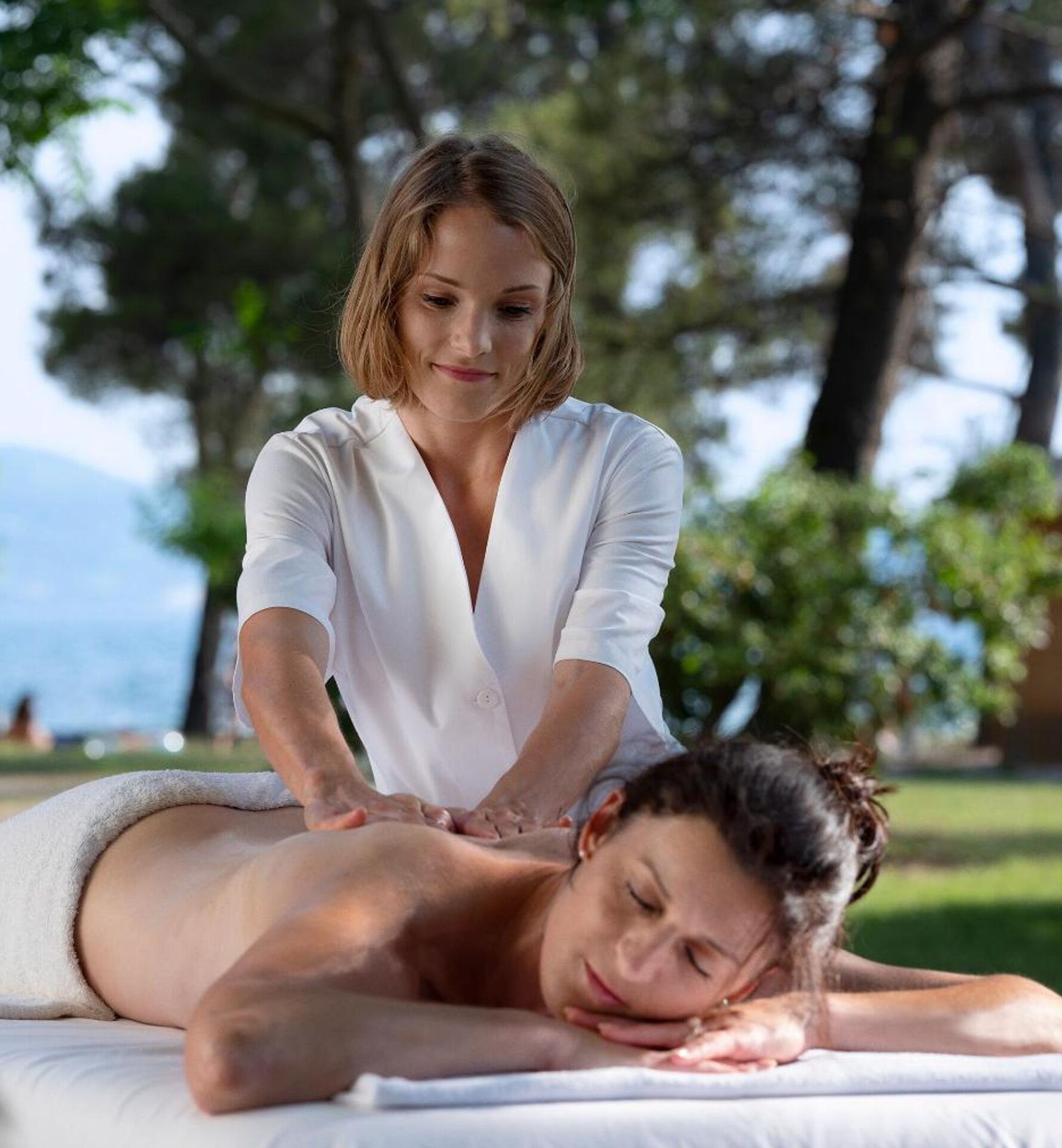 A person receiving a massage outdoors with a natural backdrop.