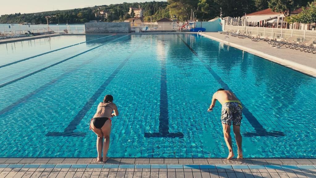 A swimming pool with clear water, marked lanes, and a tiled deck.