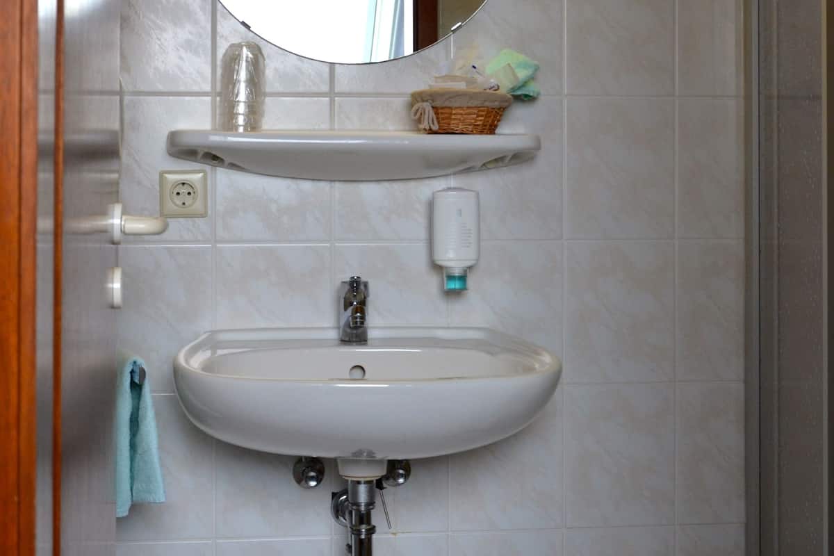 A bathroom with a sink, mirror, and shelves.