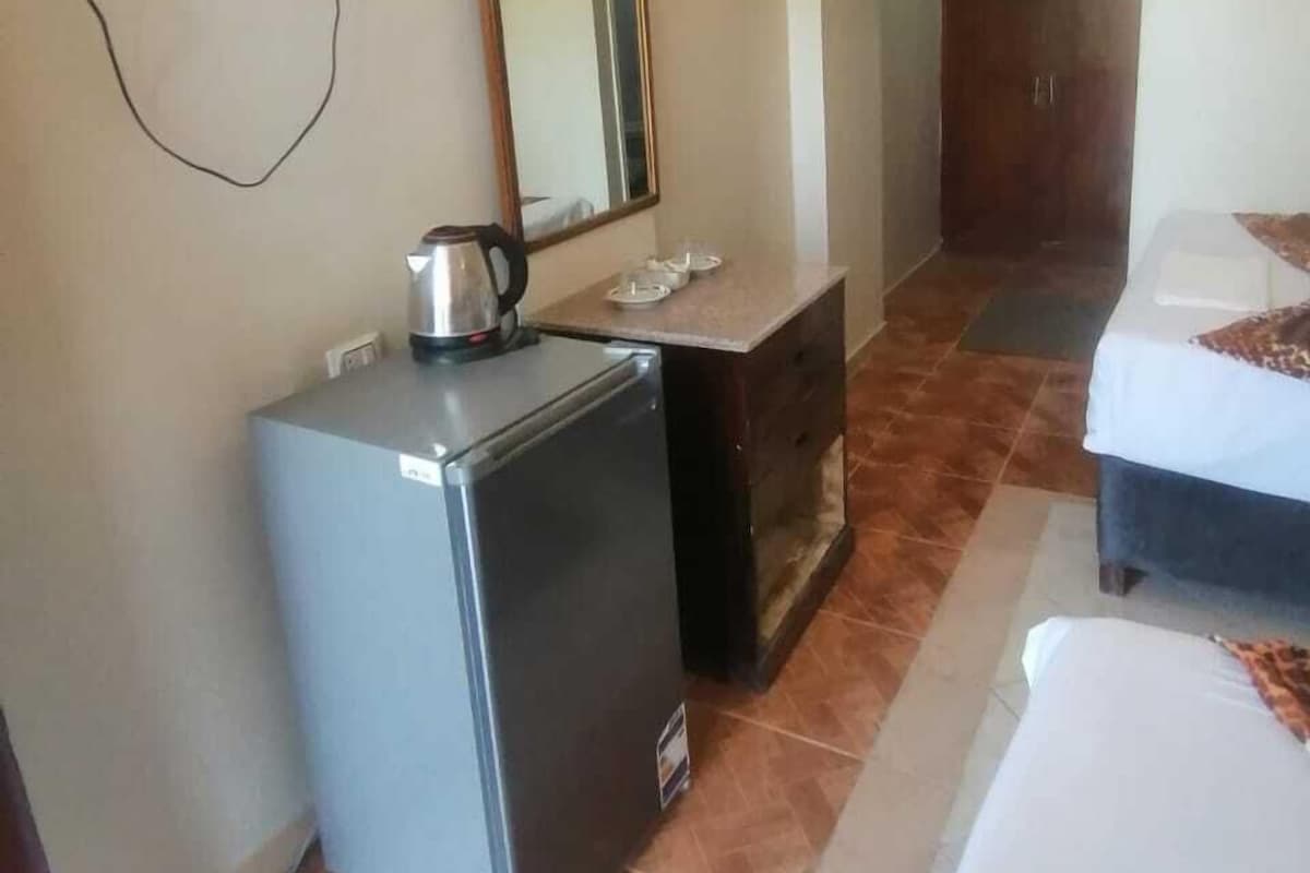 Ein kleines Hotelzimmer mit einer Küchenzeile, einem Bett, einem Kleiderschrank und einem an der Wand befestigten Fernseher.
