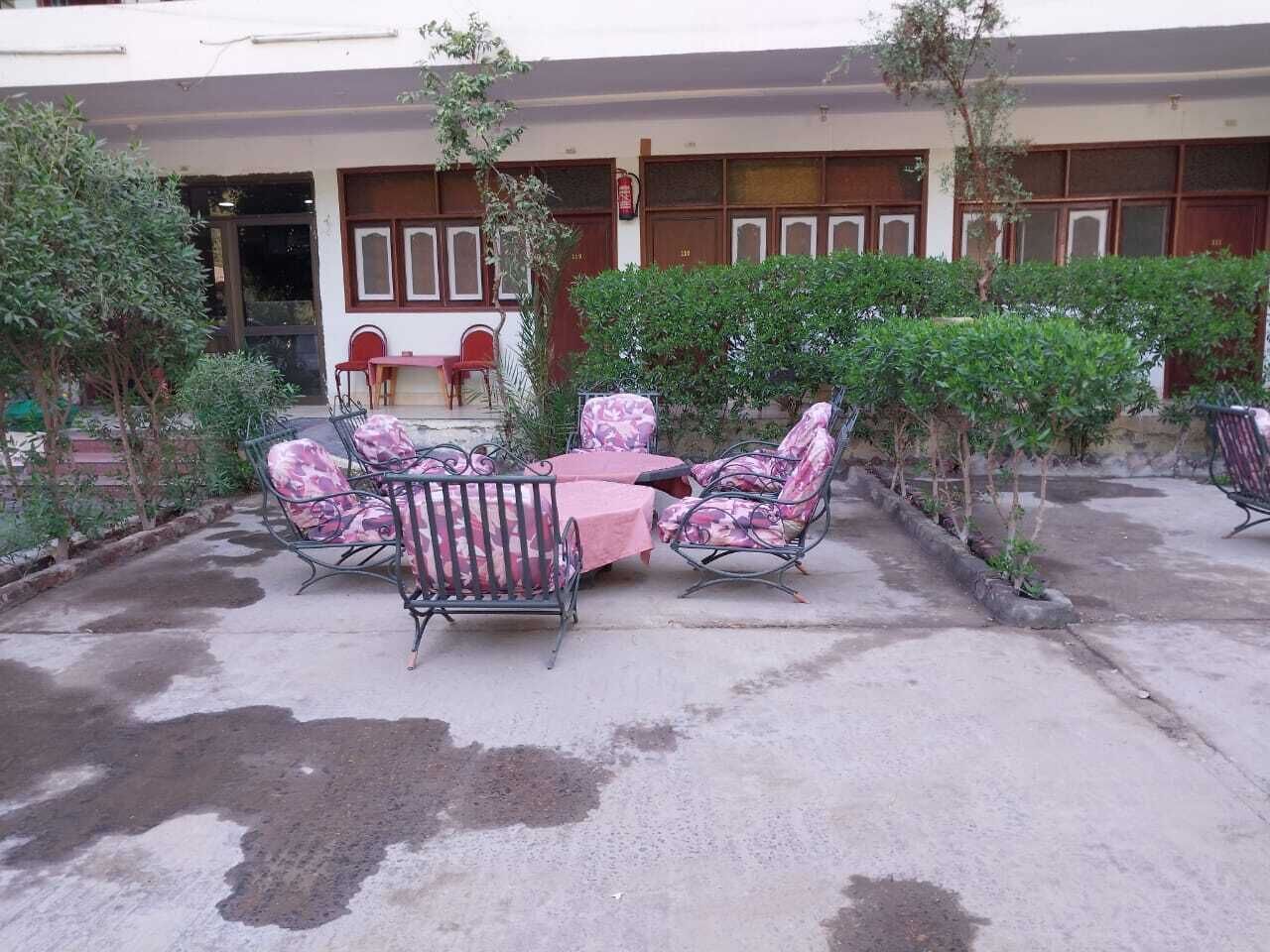 Ein sonniger Außenbereich mit einer Terrassenfläche, einem runden Tisch und vier Stühlen, umgeben von Pflanzen.