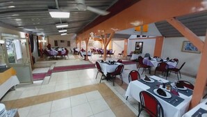 A dining area with multiple tables and chairs, arranged in a spacious indoor setting with a tiled floor and a high ceiling. - Rezeiky Hotel And Camp Luxor (Luxor)