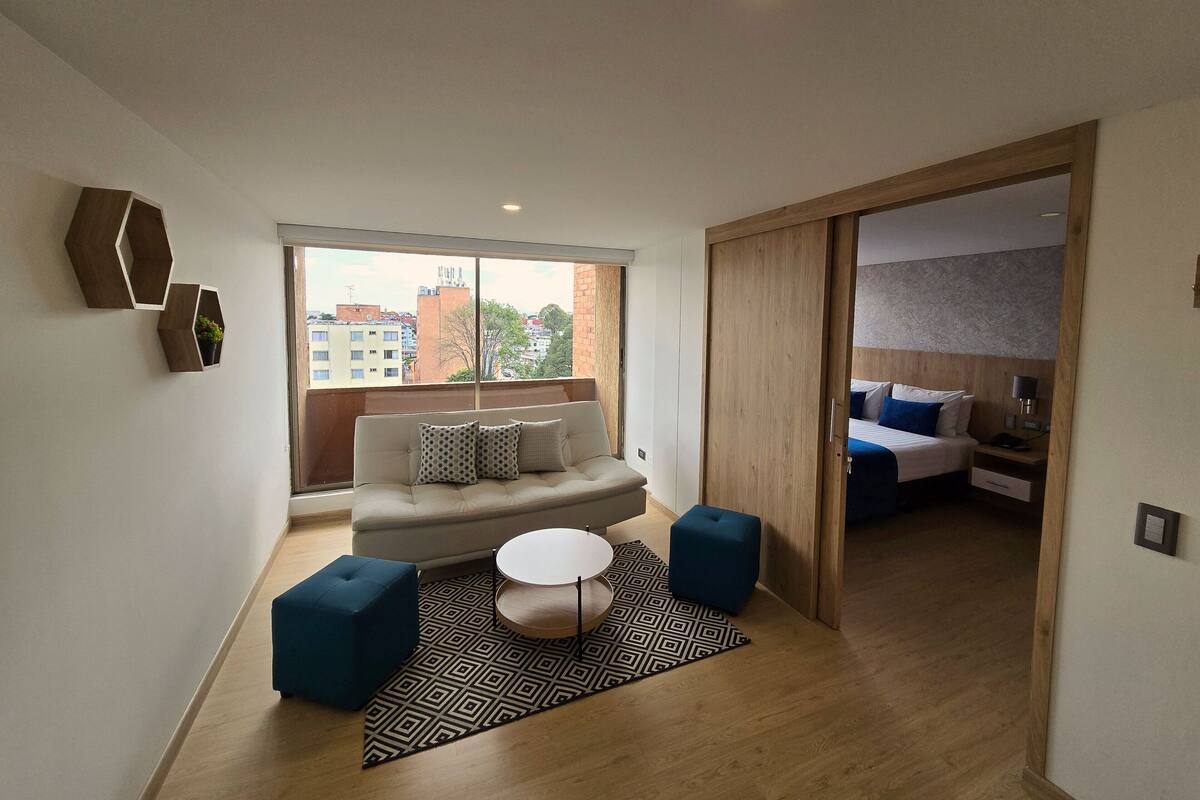 Una sala de estar moderna con un sofá, pufs, una mesa de centro y una alfombra estampada.