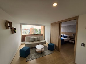 En moderne stue med sofa, skærmstole, sofabord og et tæppe med et mønster.