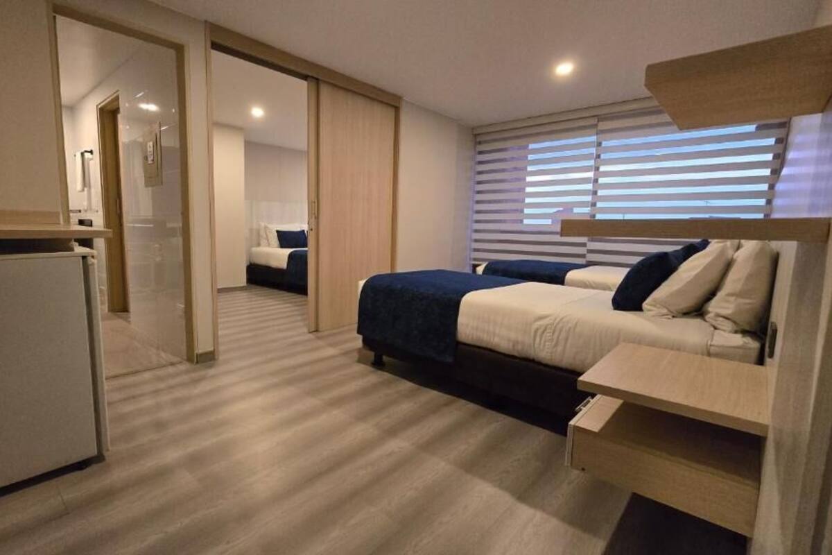 Una habitación de hotel moderna con cama, escritorio y una pequeña kitchenette.