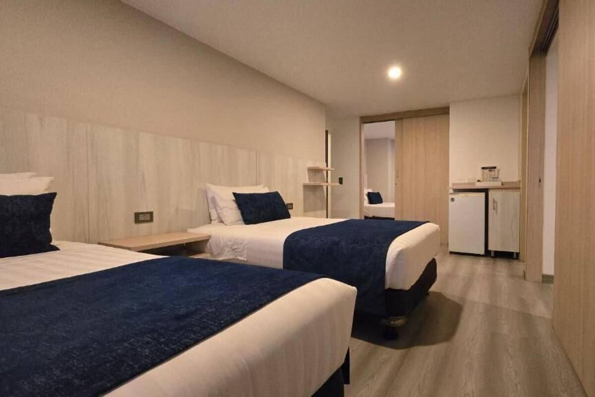 Habitación de hotel con dos camas, un escritorio, una kitchenette pequeña y un baño.