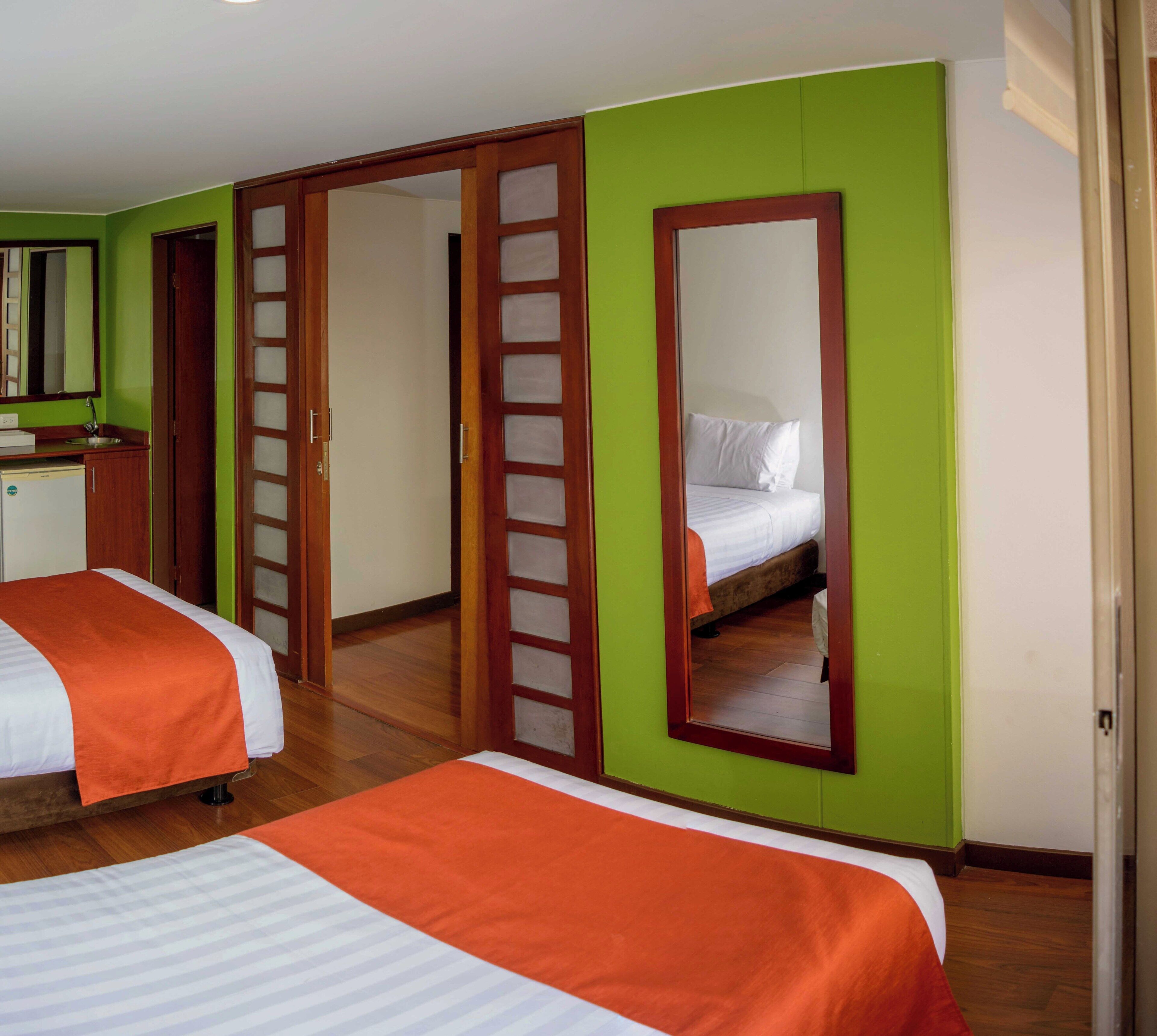 Habitació d'hotel amb dos llits, una cuineta petita i un bany.