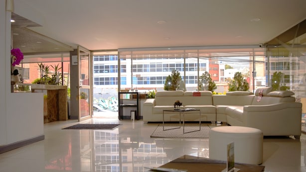 A modern hotel lobby with a white sofa, a coffee table, and a reception desk. - Hotel Confort 80 Zona Rosa (Bogotá)