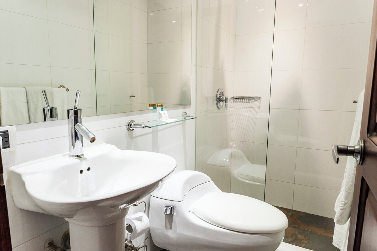 Une salle de bain moderne avec un lavabo blanc, des toilettes et une douche à parois de verre.