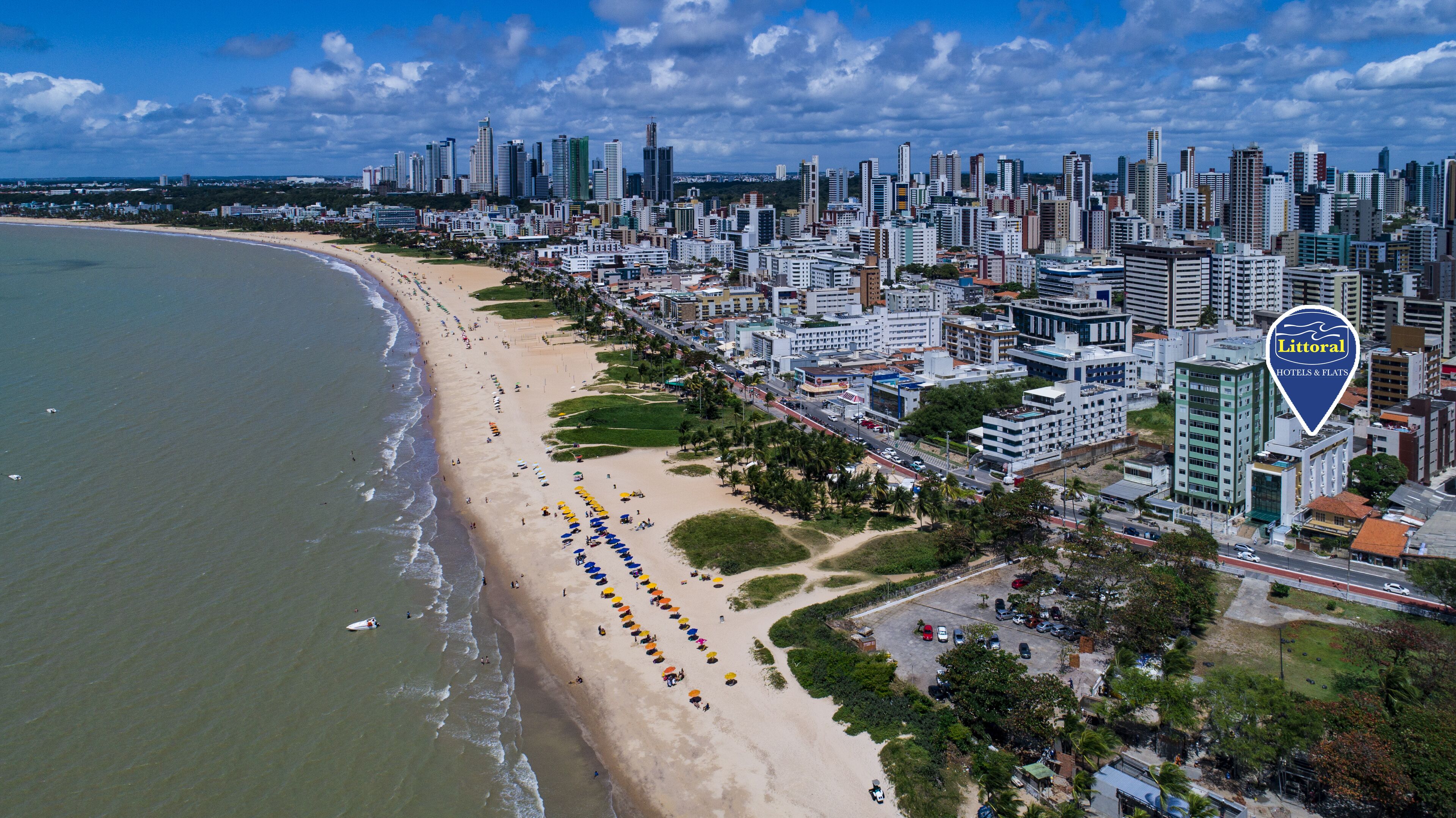 An aerial view of a coastal city with a beach, high-rise buildings, and a hotel named Litoral Hotels & Flats.