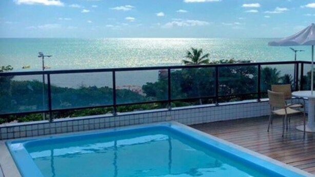 Una piscina con vista al océano y una zona de estar cubierta.