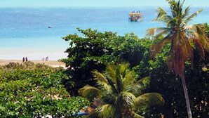 Una playa con agua azul cristalina, un bote y palmeras.