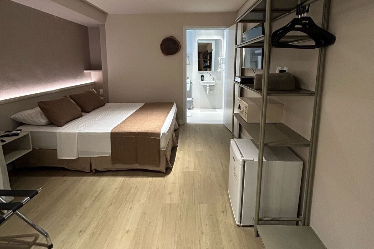 A compact room with a bed, a desk, and a walk-in closet with shelves and a hanging rack.