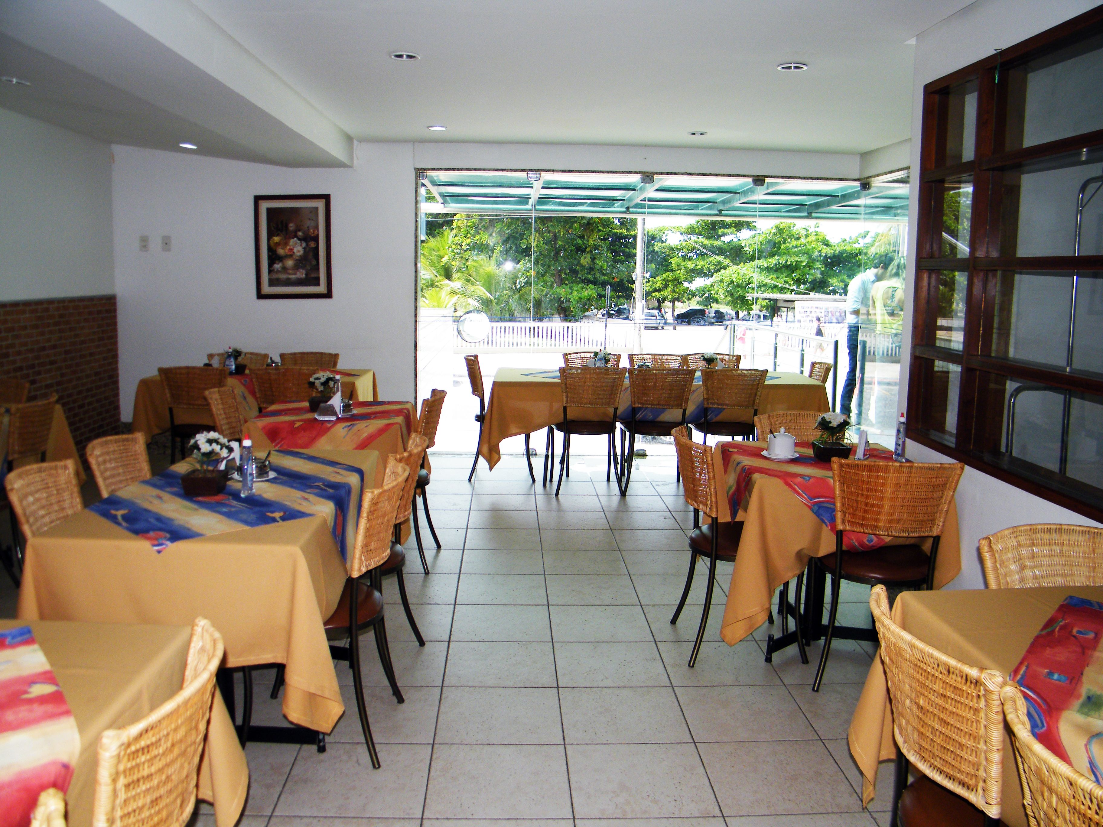 Un ristorante con diversi tavoli e sedie, un pavimento piastrellato e vista all'esterno.