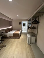 Un dormitorio pequeño con cama, mesita de noche y armario con espacio para colgar ropa.