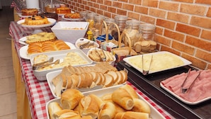 Una mesa de buffet con diversas opciones de comida, como pan, pasteles y sándwiches.