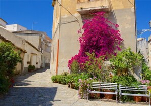 A narrow cobblestone street with a bench and potted plants. - Il Nocchiero City Hotel (Soverato)