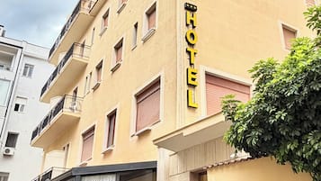 A hotel with a yellow facade, a staircase leading to the entrance, and a sign indicating it is a 3-star establishment.