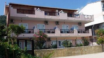 Un edificio residencial de varios pisos con balcones, unidades de aire acondicionado y un muro de contención de piedra.