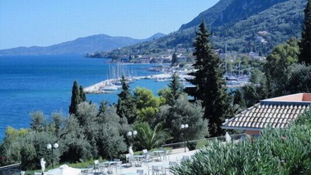 Vista sulla costa con una montagna sullo sfondo, cielo sereno e un corpo d'acqua.