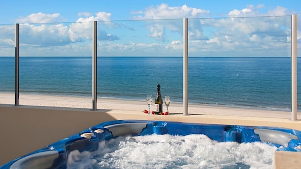 A beachside hot tub with a bottle and glasses, overlooking the sea. - On the Beach Resort Bribie Island (Woorim)