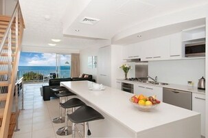 Una cocina moderna con una isla grande, taburetes de bar y vista al océano.