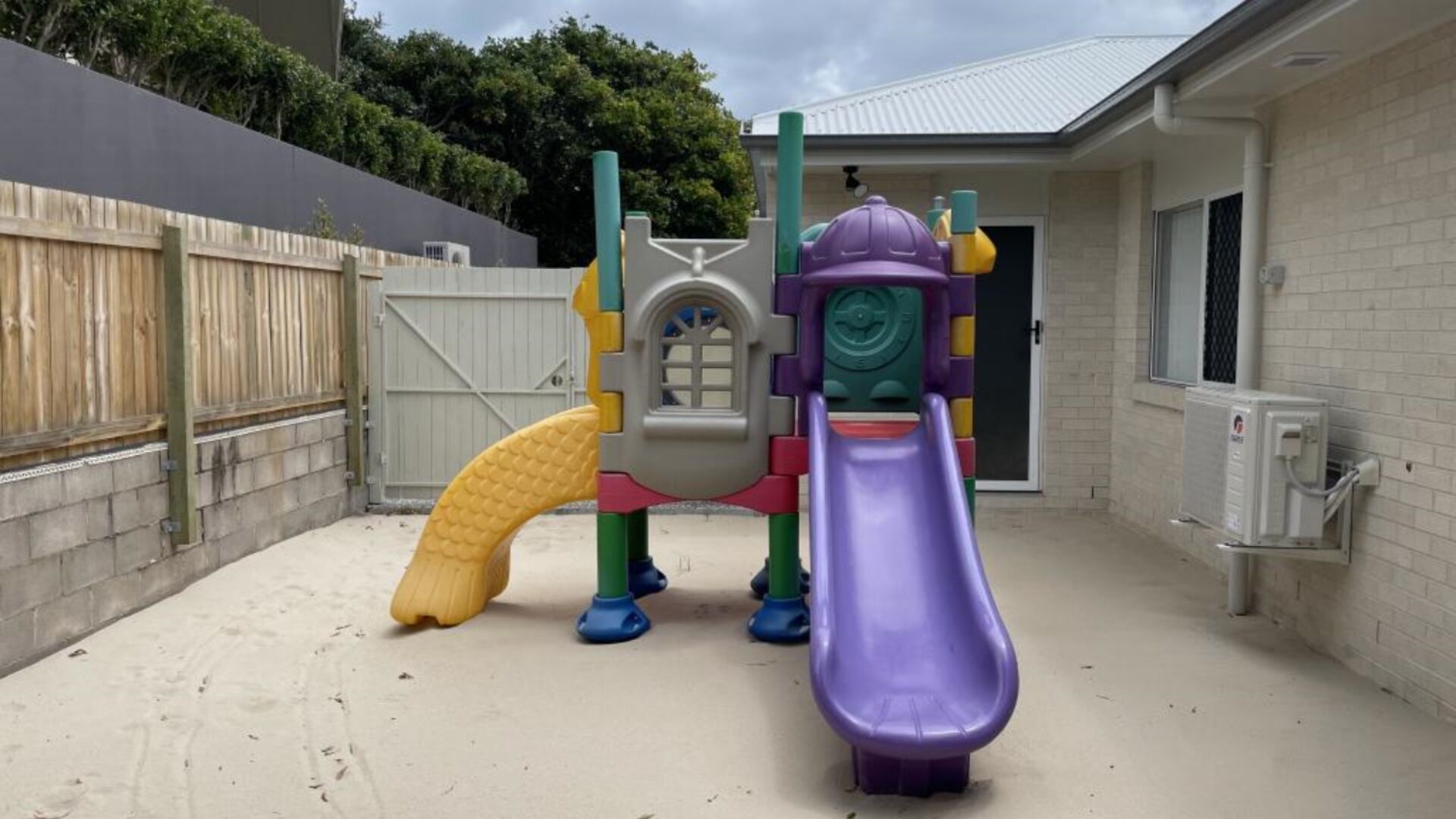 A playground with a purple slide and a yellow climbing structure.